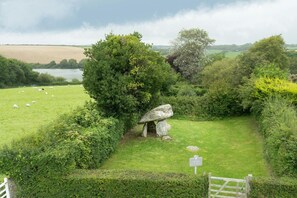 A stone circle in a grassy field with sheep grazing nearby and a lake in the background. - Carreg Coetan Cottage, Newport (Newport)