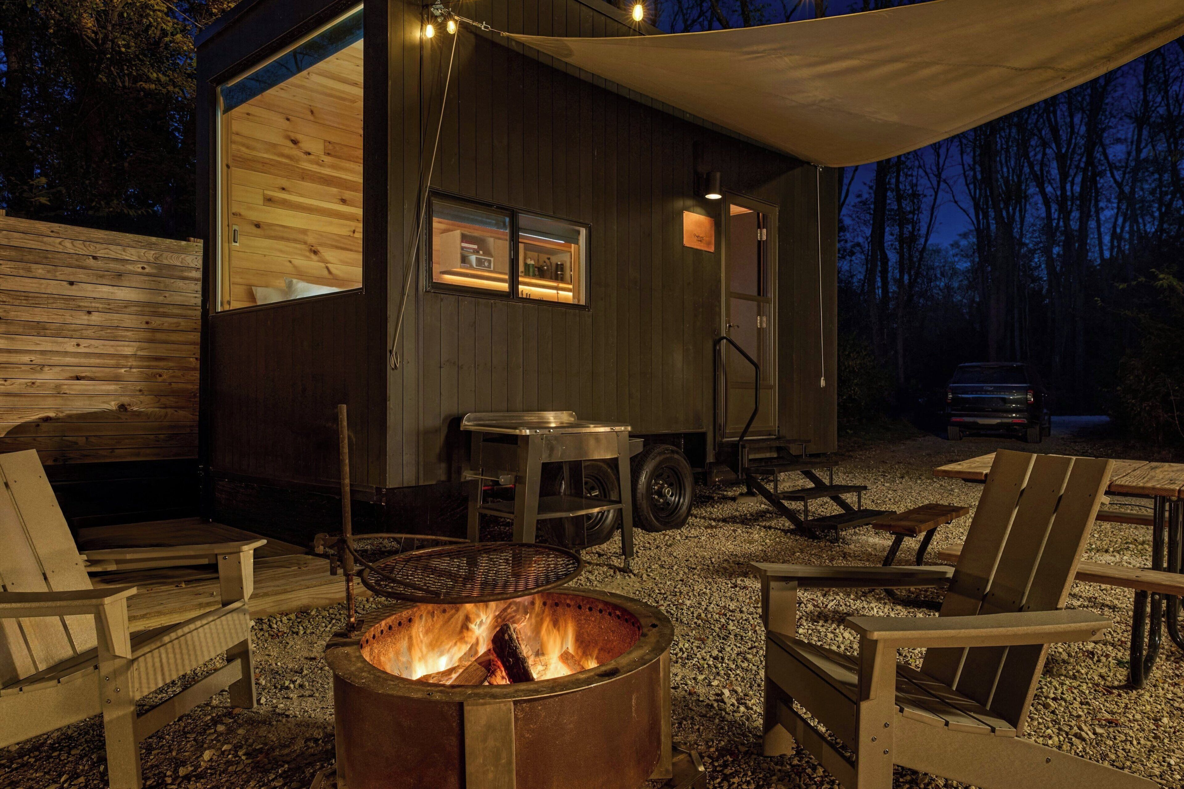 A rustic cabin with a fire pit, wooden furniture, and a covered outdoor area.