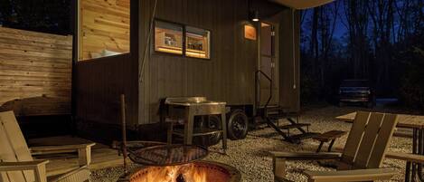 A rustic cabin with a fire pit, wooden furniture, and a covered outdoor area.