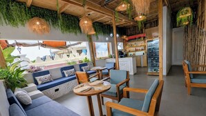 Un café acogedor con mobiliario de madera, plantas colgantes y una zona de bar.