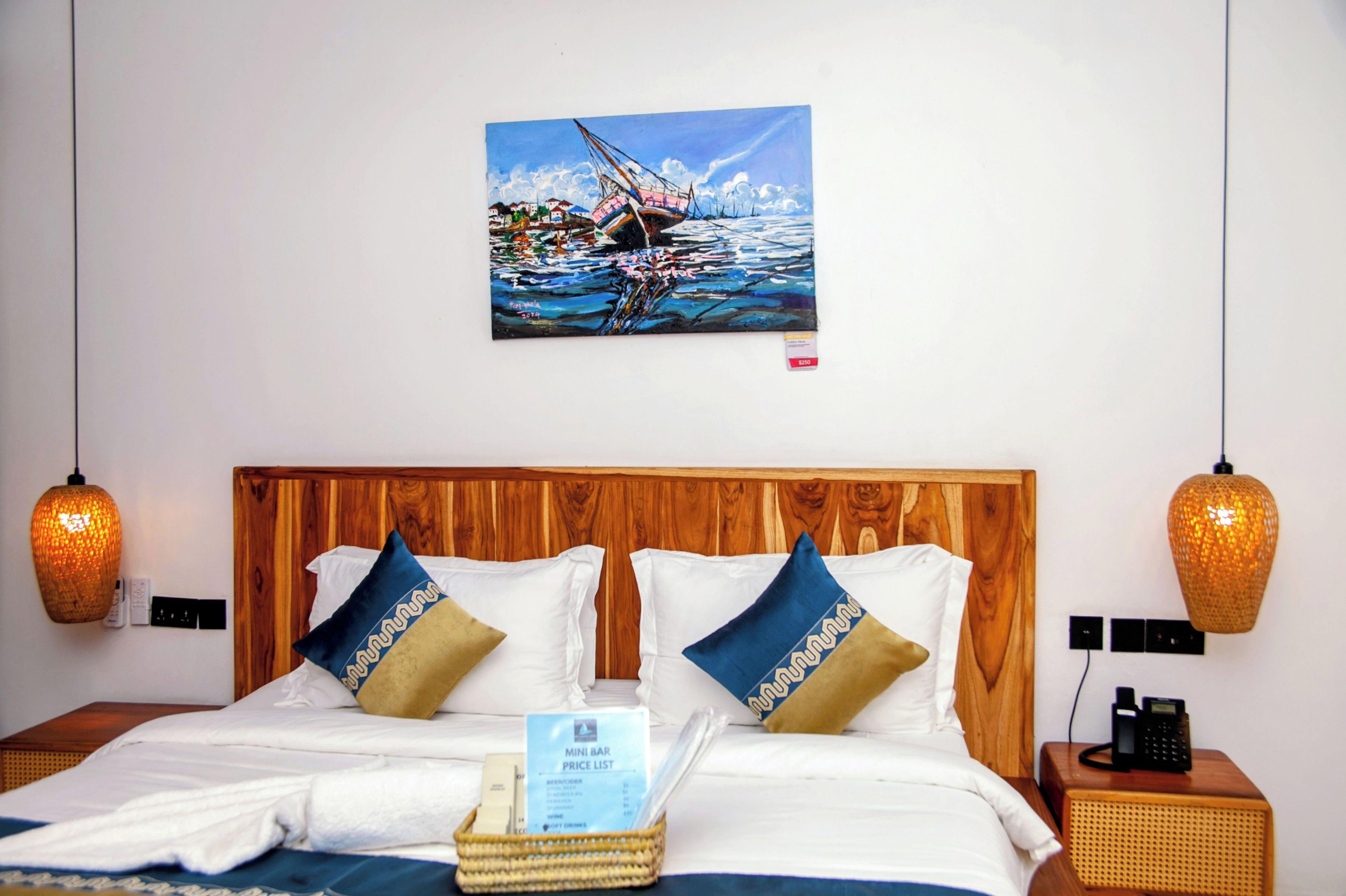 A hotel room with a wooden headboard, white bedding, and decorative pillows. A painting of a boat on water hangs on the wall.