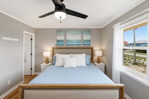 A bedroom with a bed, two bedside tables, a ceiling fan, and a window with a view. - Honey Hole on St George Island Pet Friendly Private Pool (Heated for a fee) West Gulf beaches (Saint George Island)