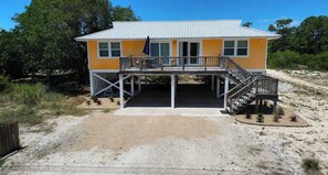 A two-story building with a deck, a covered area, and a sandy ground. - Honey Hole on St George Island Pet Friendly Private Pool (Heated for a fee) West Gulf beaches (Saint George Island)