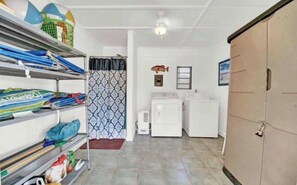 A laundry room with a washing machine, dryer, and shelves with cleaning supplies.