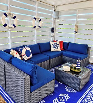 A nautical-themed seating area with a sofa and two side tables, life rings, and a ship's wheel pillow.