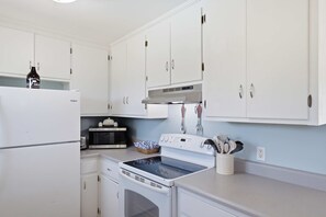 A kitchen with white cabinets, a microwave, a stove, and a refrigerator.
