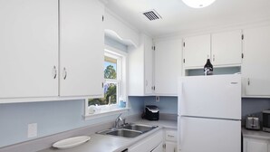Una cocina moderna con armarios blancos, un lavamanos de acero inoxidable y un horno empotrado.