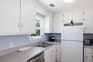 Una cocina moderna con armarios blancos, un lavamanos de acero inoxidable y un horno empotrado.