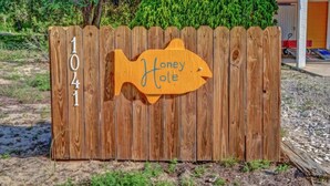 Una cerca de madera con un letrero con forma de pez que dice 'Honey Hole' y el número '1041'.