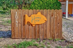 A wooden fence with a fish-shaped sign that reads 'Honey Hole' and the number '1041' on it. - Honey Hole on St George Island Pet Friendly Private Pool (Heated for a fee) West Gulf beaches (Saint George Island)