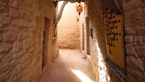 A narrow stone corridor with hanging lanterns and patterned wall decorations. - Dar Tantora The House Hotel (Al-'Ula)