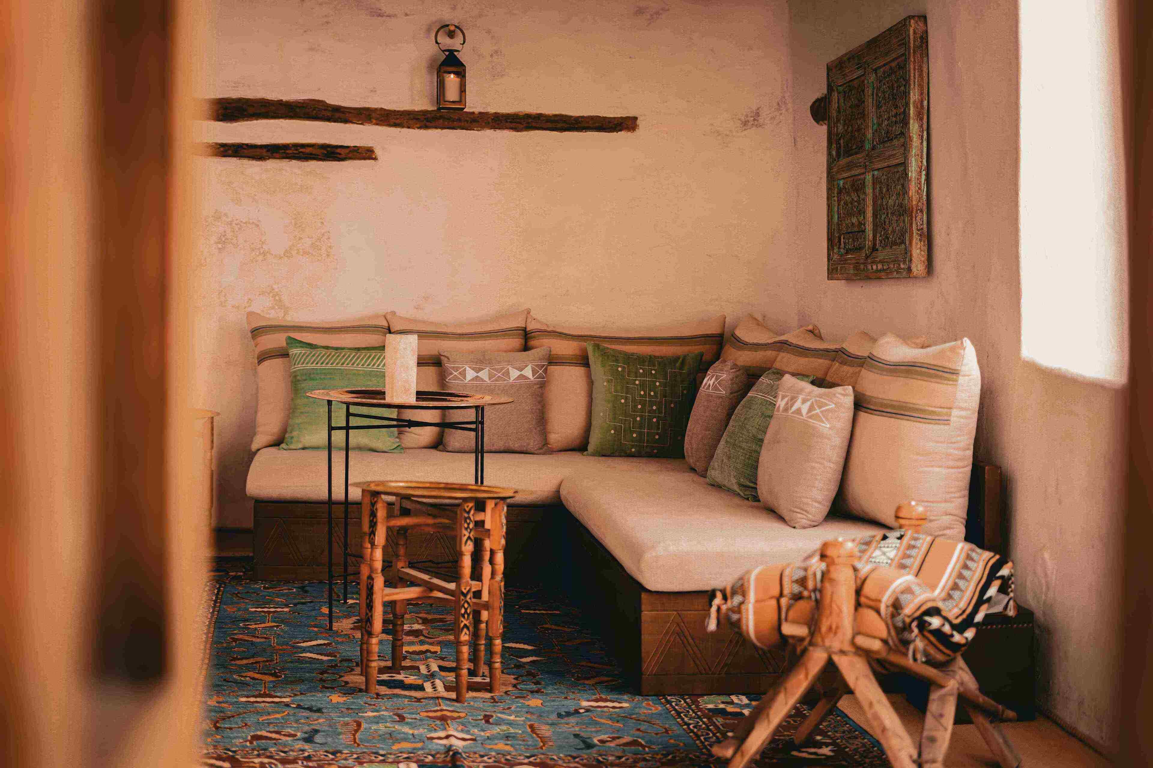 A cozy room with a sofa, a small table, a hanging lantern, and a patterned rug.