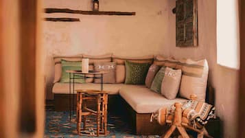 A cozy room with a sofa, a small table, a hanging lantern, and a patterned rug.