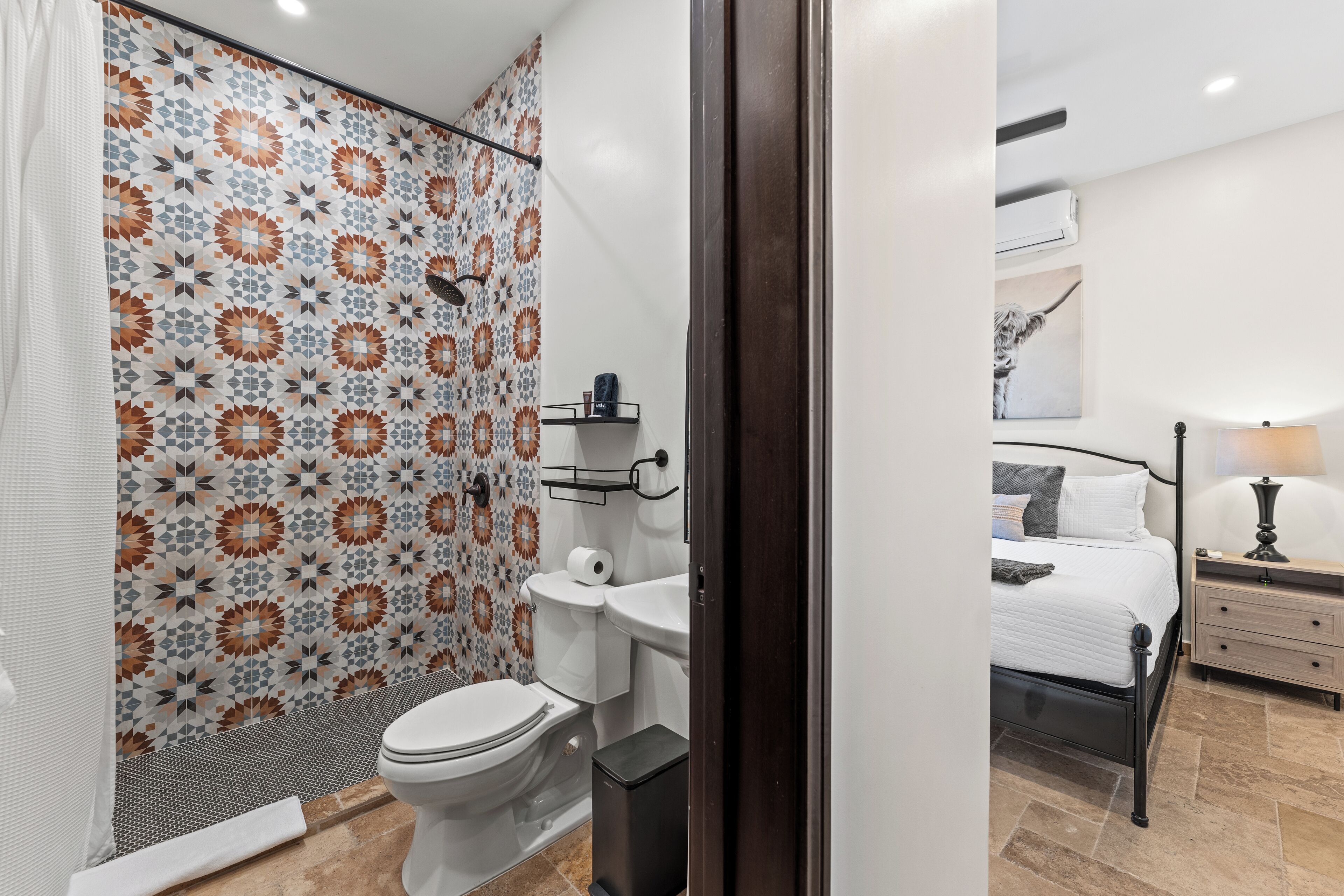 Ein Badezimmer mit Dusche, Toilette und Waschbecken sowie ein Schlafzimmer mit Bett und Nachttisch.