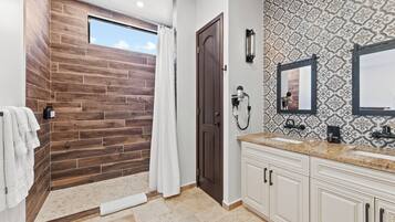 Un baño con una pared de acento de madera, una ducha, un espejo grande y un tocador con lavabo.