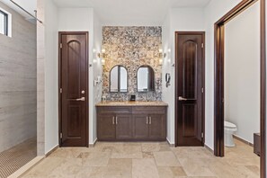 A modern bathroom with a tiled backsplash, two sinks, dark wooden cabinets, and a toilet. - Las Haciendas (San Ignacio)