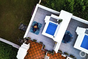 An aerial view of a modern house with a swimming pool, a patio with outdoor furniture, and a garden area. - Las Haciendas (San Ignacio)