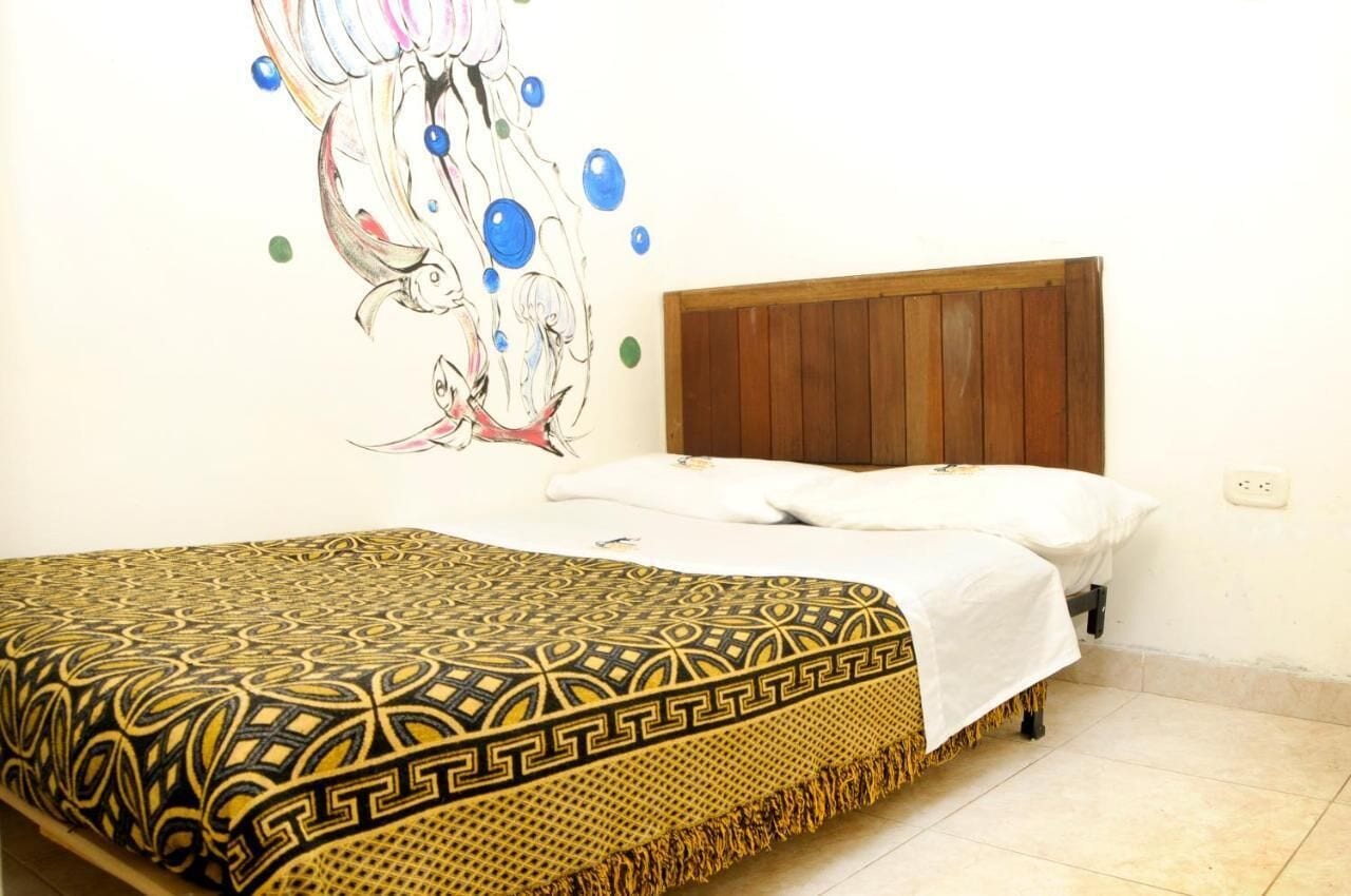 A bedroom with a bed, a wooden headboard, and a wall mural.