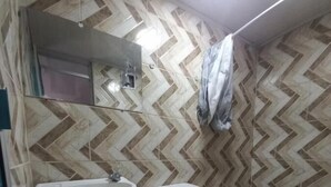 A bathroom with a white sink, toilet, and a mirror. The walls have a chevron tile pattern. - Hostal Chorro De Quevedo Candelaria (Bogotá)