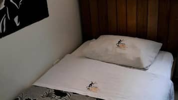 A single bed with a floral-patterned bedspread, a white pillow, and a wooden headboard.