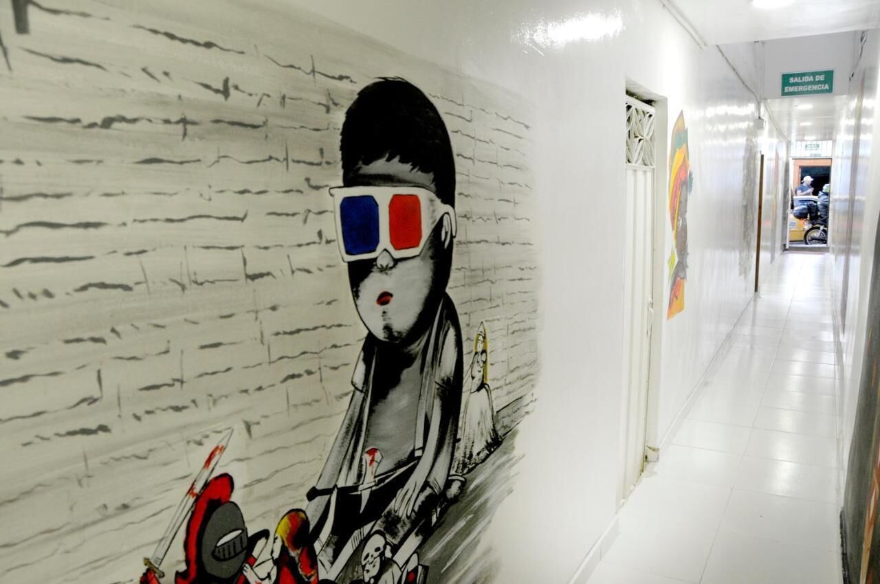 A corridor with a mural of a person wearing 3D glasses and holding a toy car.