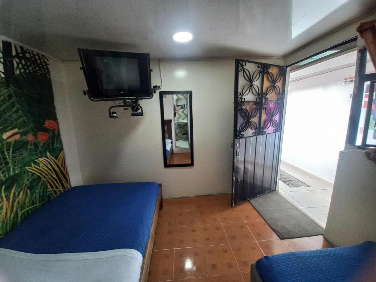 A room with two beds, a TV, a mirror, and a decorative metal gate.