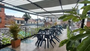 A covered outdoor seating area with chairs and potted plants. - Hostal Chorro De Quevedo Candelaria (Bogotá)