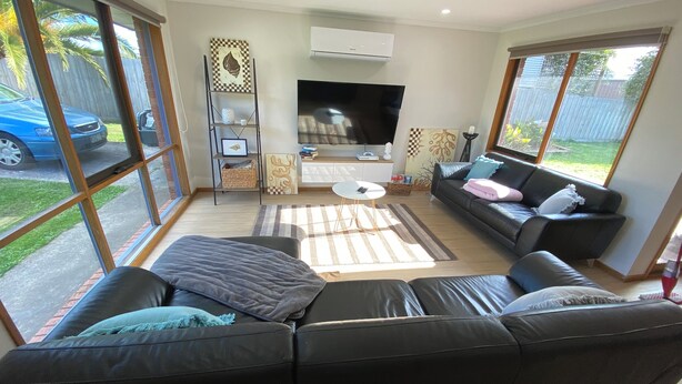 A modern living room with a black leather sofa, a flat-screen TV, and a large window offering a view of the outside. - LUXURY 4 BEDROOM KING BED SPA ARCADE WIFI NETFLIX SLEEPS 10 WITH BOAT PARKING (Portland)
