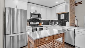 A modern kitchen with stainless steel appliances, white cabinetry, and a central island.