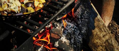 A grill with vegetables and corn on a fire.