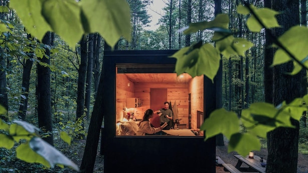 A cabin with a cozy interior, a dining area, and a view of the forest. - Postcard Cabins Gilchrist Springs, Outdoor Collection by Marriott Bonvoy (High Springs)
