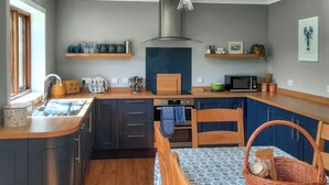Une cuisine moderne avec des meubles de couleur sombre, des plans de travail en bois et une nappe bleue à motifs.
