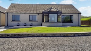 Une maison moderne à deux étages, dotée d’un toit en tuiles, d’un porche couvert et d’une pelouse bien entretenue.