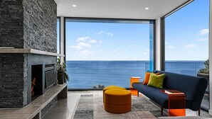 Una sala de estar moderna con chimenea, un sofá y vista al océano.