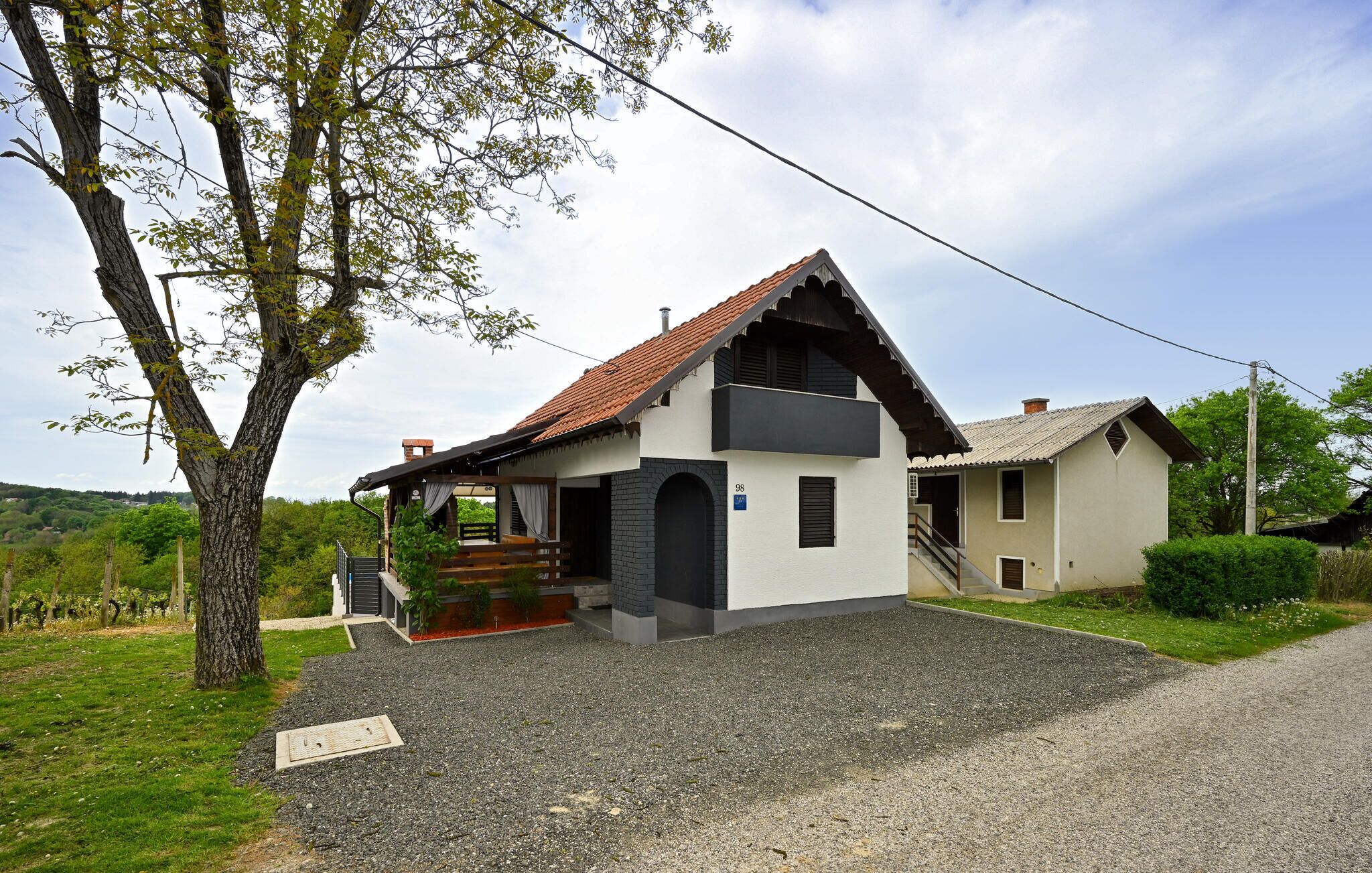 A two-story house with a sloped roof, a porch, and a gravel driveway.