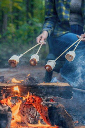 A person roasting marshmallows over a campfire. - Postcard Cabins Beaver Creek, Outdoor Collection by Marriott Bonvoy (Lisbon)