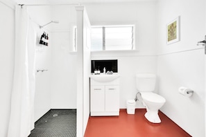 A bathroom with a shower, toilet, sink, and a window above the sink.