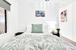A bedroom with a bed, a nightstand with a lamp, and two wall art pieces.