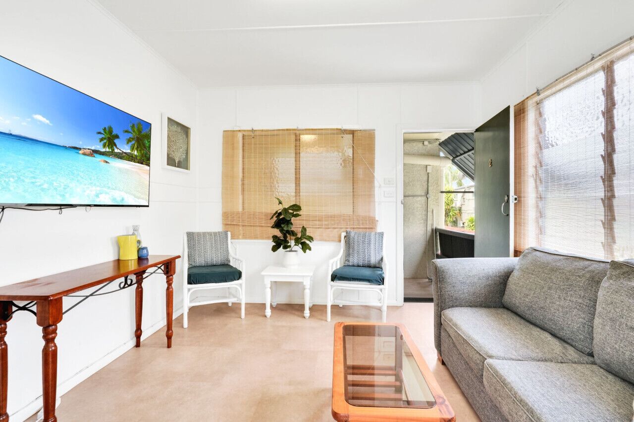 A living room with a TV, a sofa, a coffee table, and two chairs.