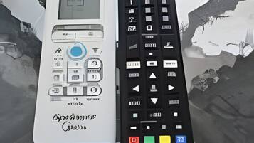 Dos controles remotos sobre una superficie reflectante.