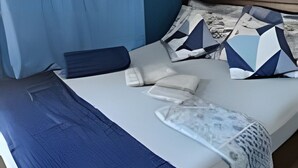 Una cama con colcha azul, almohadas y manta.