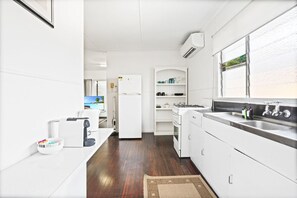 Una cocina moderna con armarios blancos, un lavamanos de acero inoxidable y vistas al exterior a través de una ventana.
