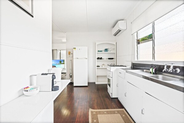 A modern kitchen with white cabinetry, a stainless steel sink, and a view of the outdoors through a window.