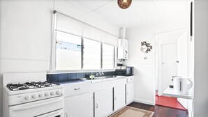 Una cocina moderna con armarios blancos, estufa a gas, microondas y piso rojo.