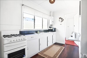 A modern kitchen with white cabinets, a gas stove, a microwave, and a red floor.