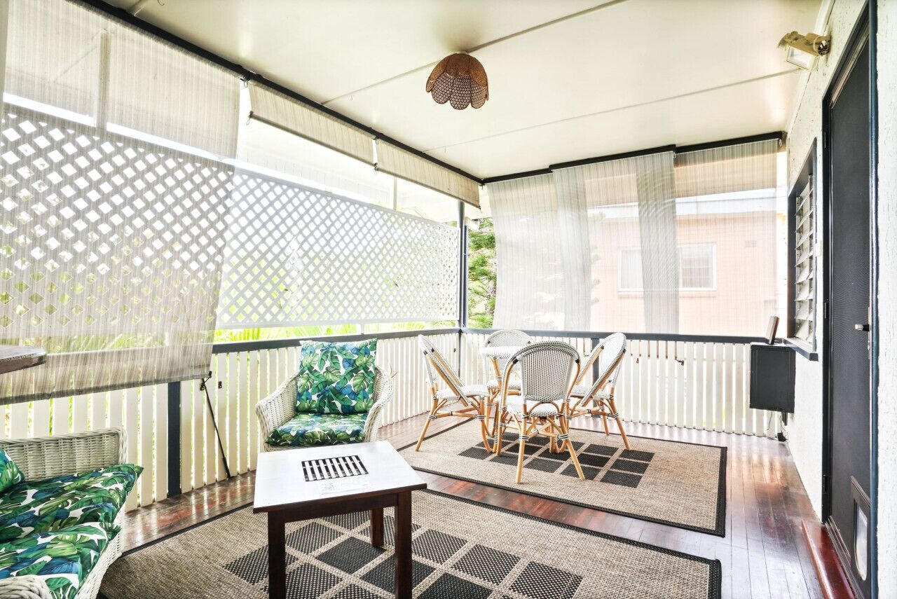 A balcony with a wicker sofa, a small table, and a dining set.