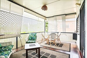 A balcony with a wicker sofa, a small table, and a dining set.