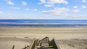 Ein Strand mit einer Holzstege, der zum Wasser führt.