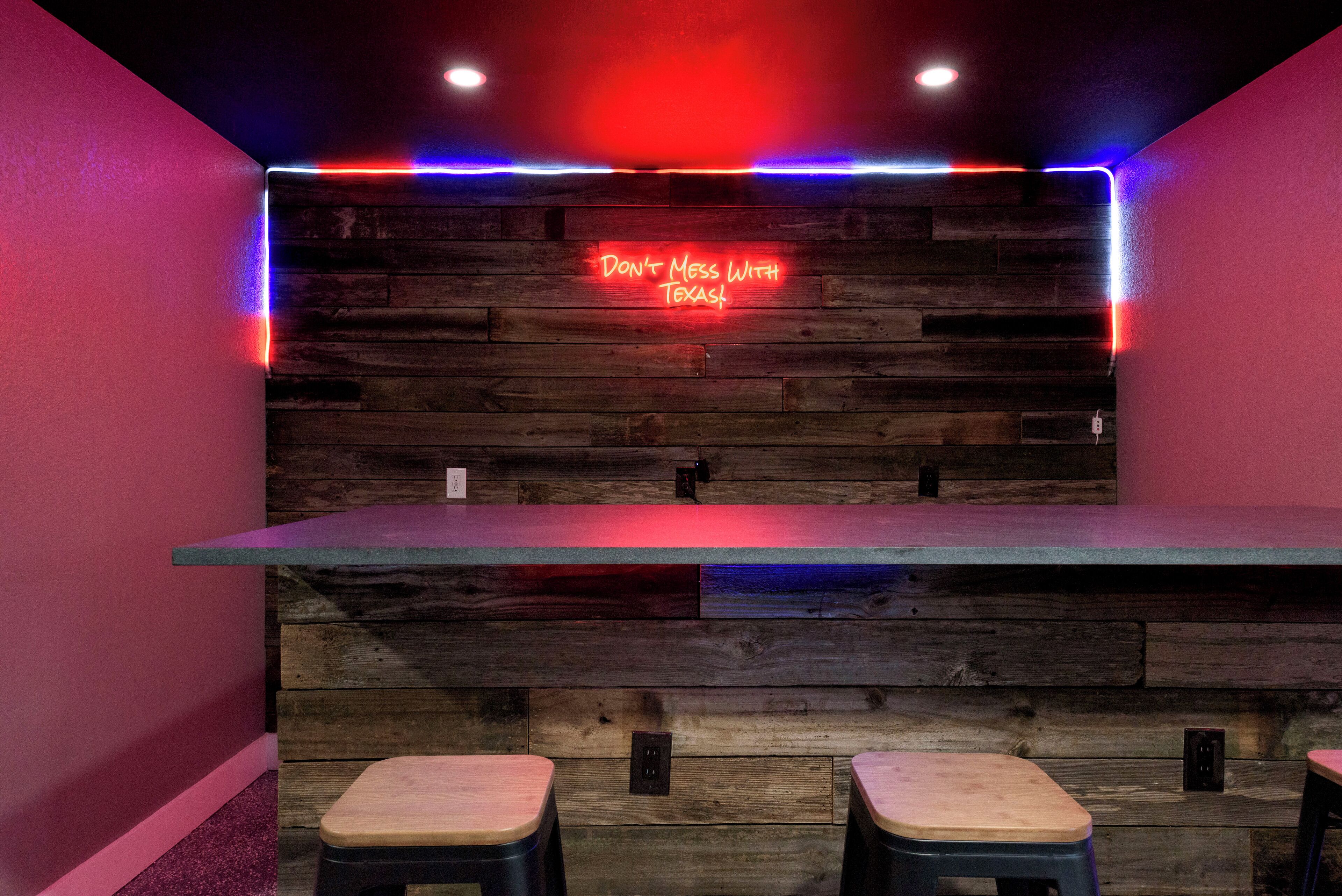 A bar area with a neon sign reading "Don't Mess With Texas" and wooden paneling.