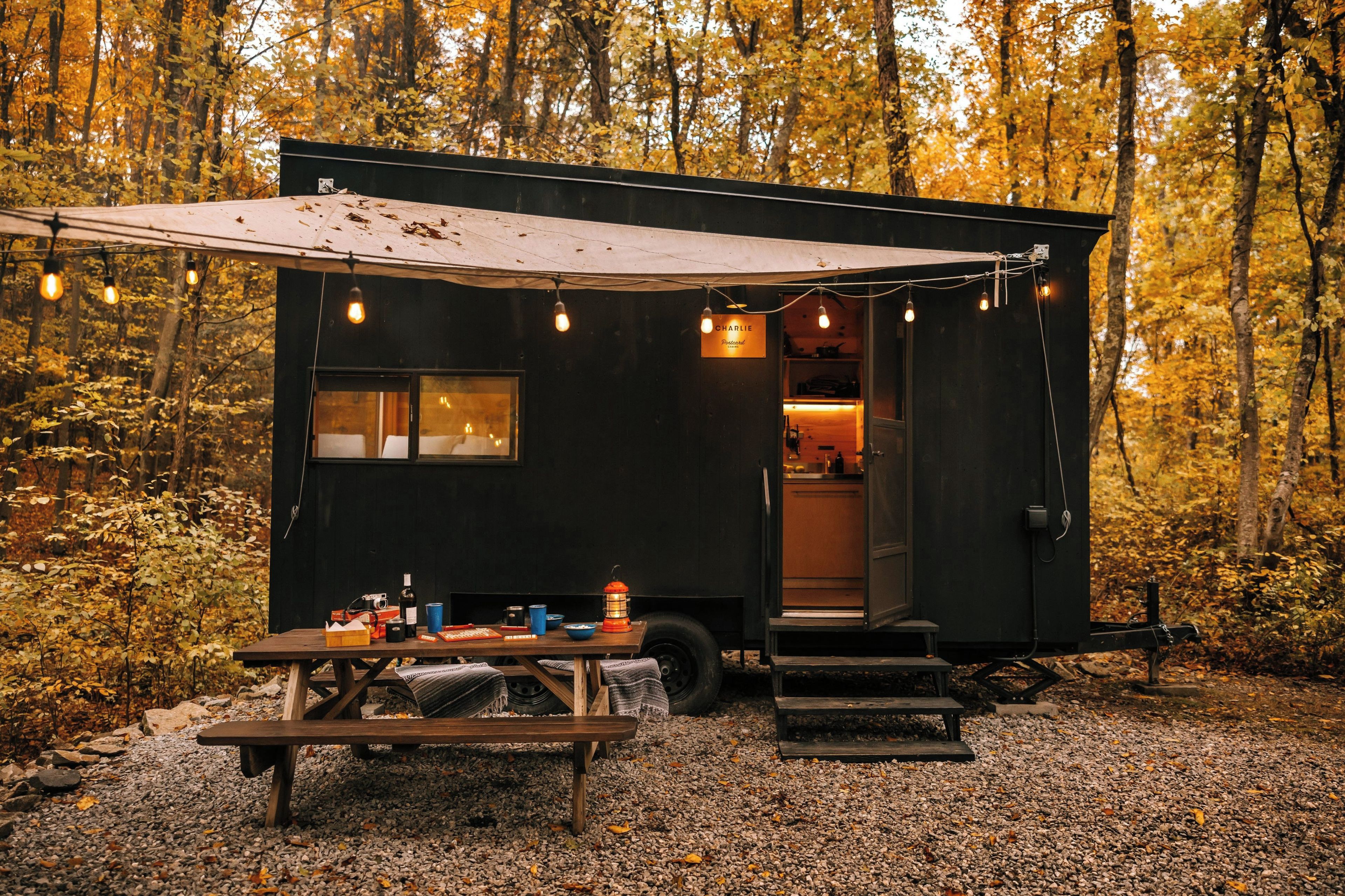 Une petite cabane noire avec une table de pique-nique, un banc et une lanterne.